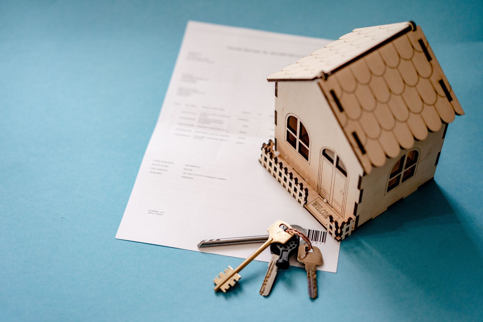 House model and keys next to a home sale document