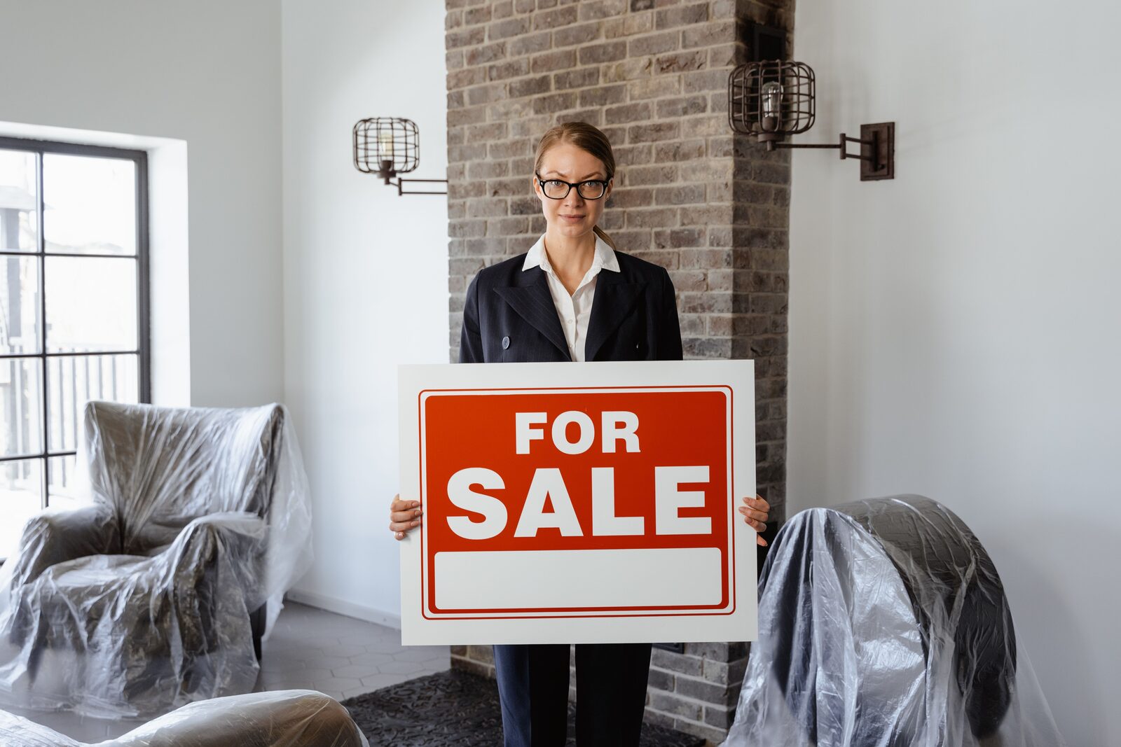 Homeowner holding a for sale sign while preparing to move